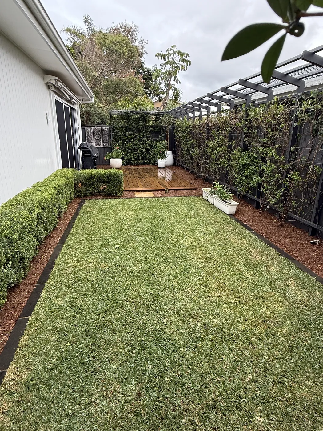 Manicured garden and lawn beside a pergola seating area