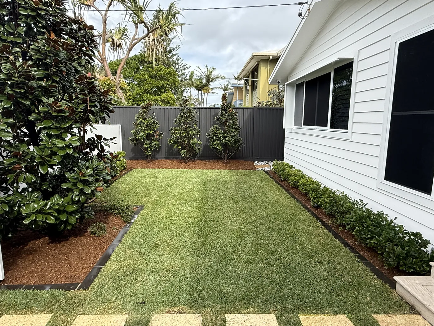 Tidy side garden with mulched beds and young hedges