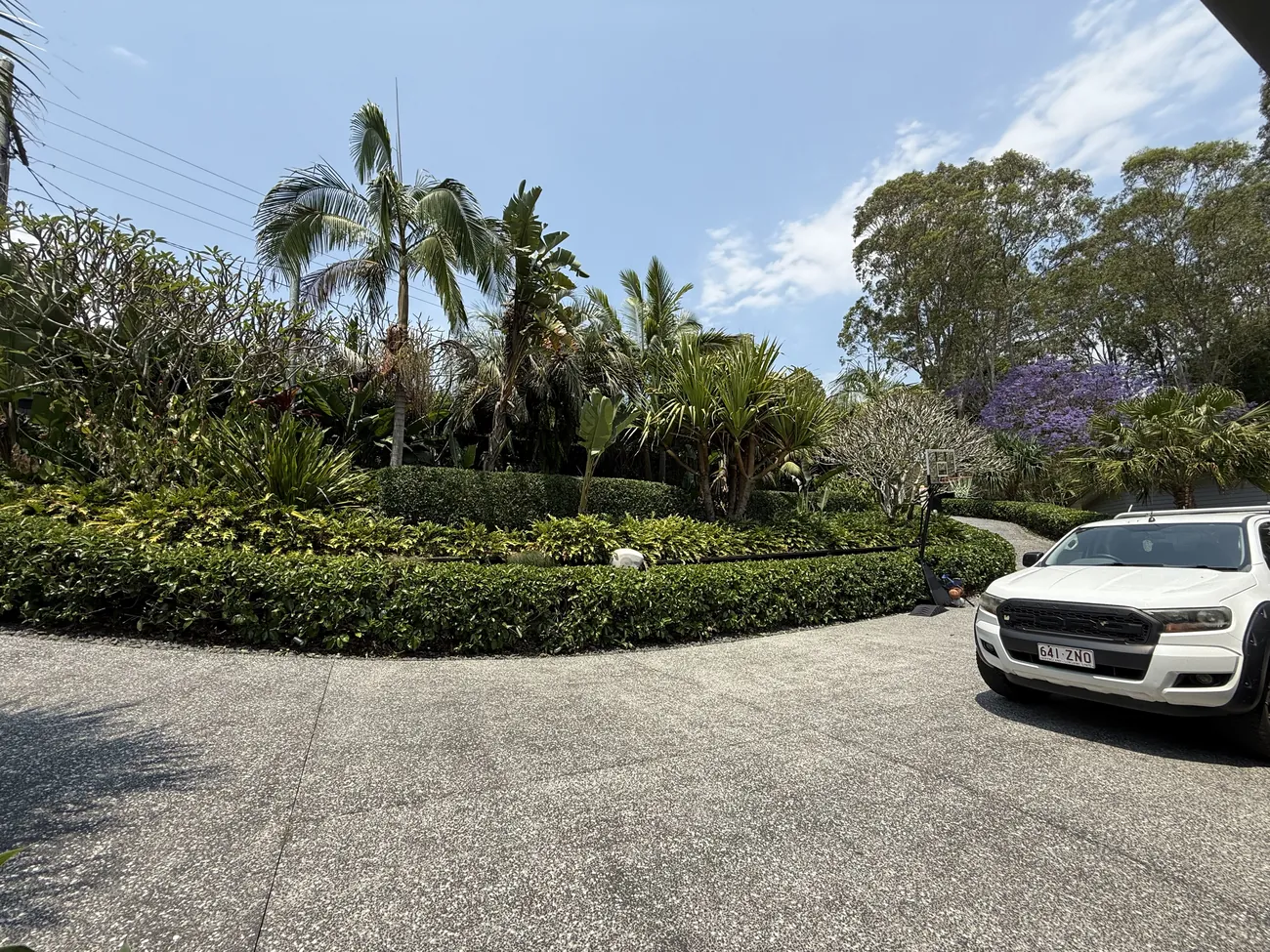 Manicured estate garden with hedges, palms and the work ute