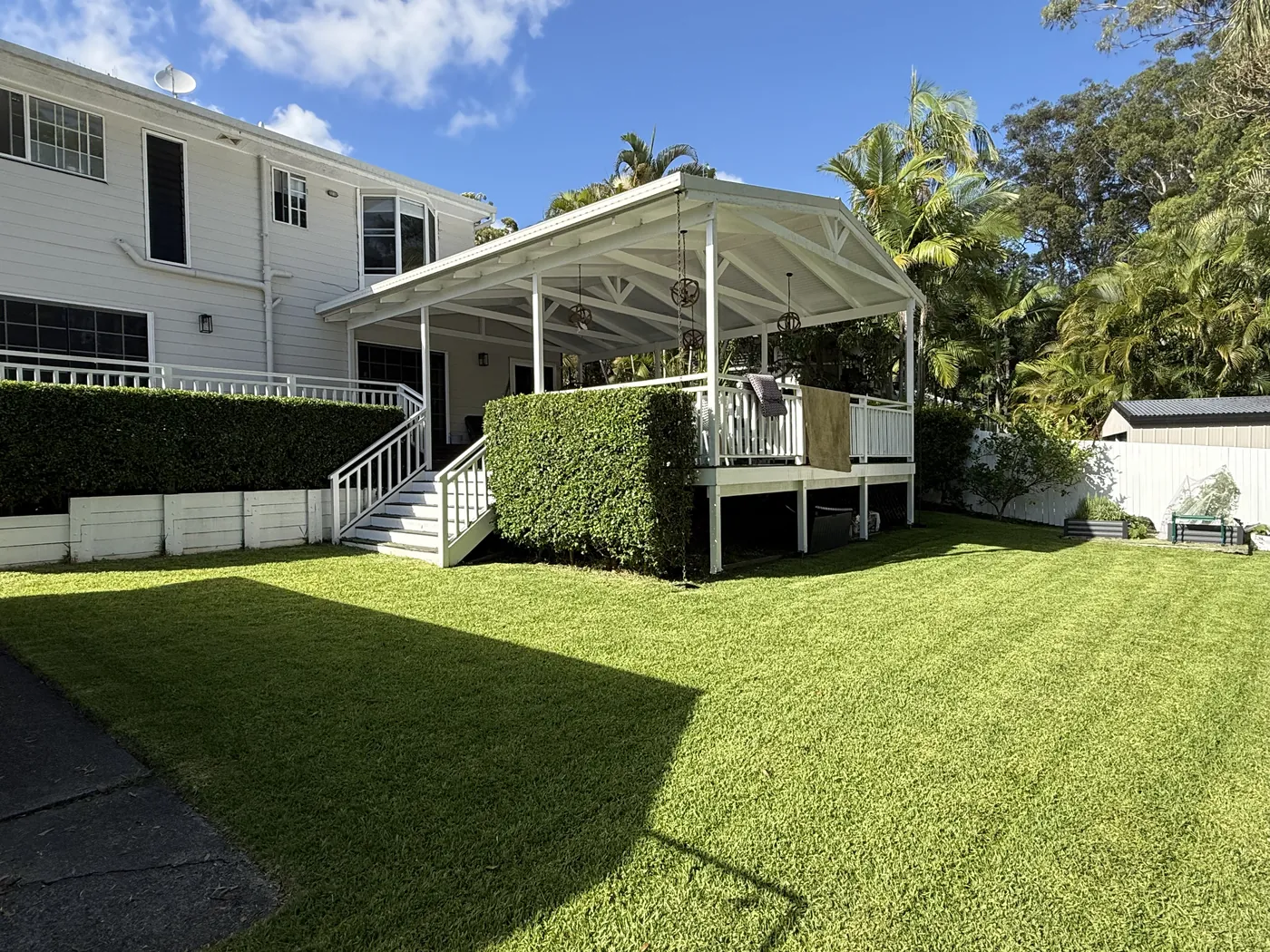 Tidy backyard lawn with a shaped hedge under the deck