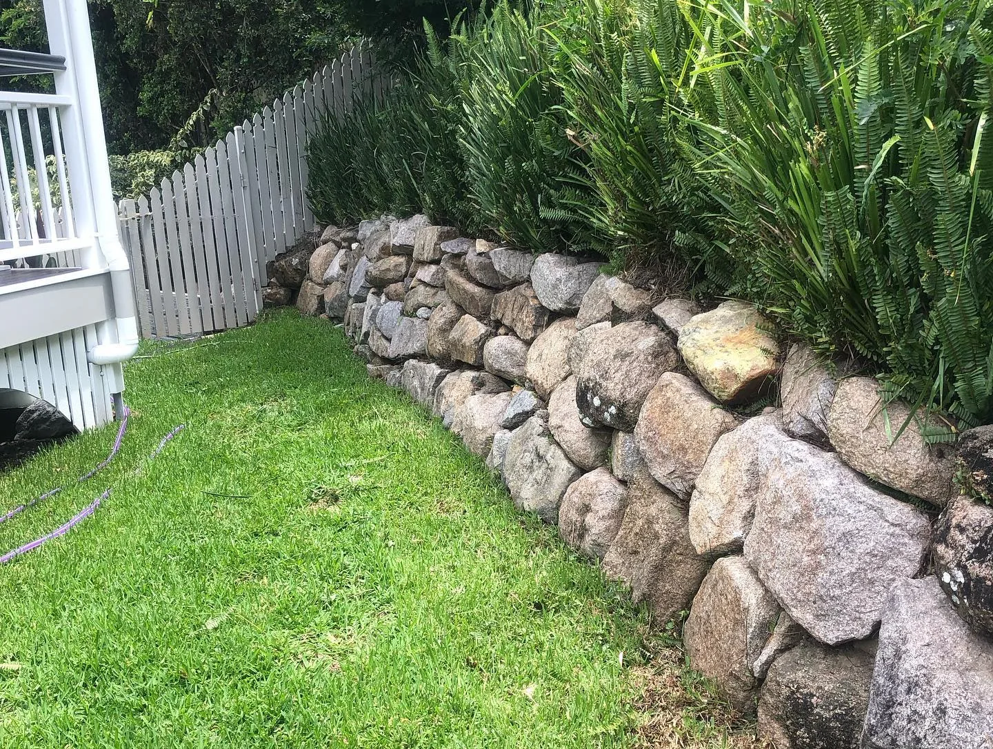 Mulched garden bed by a stone wall